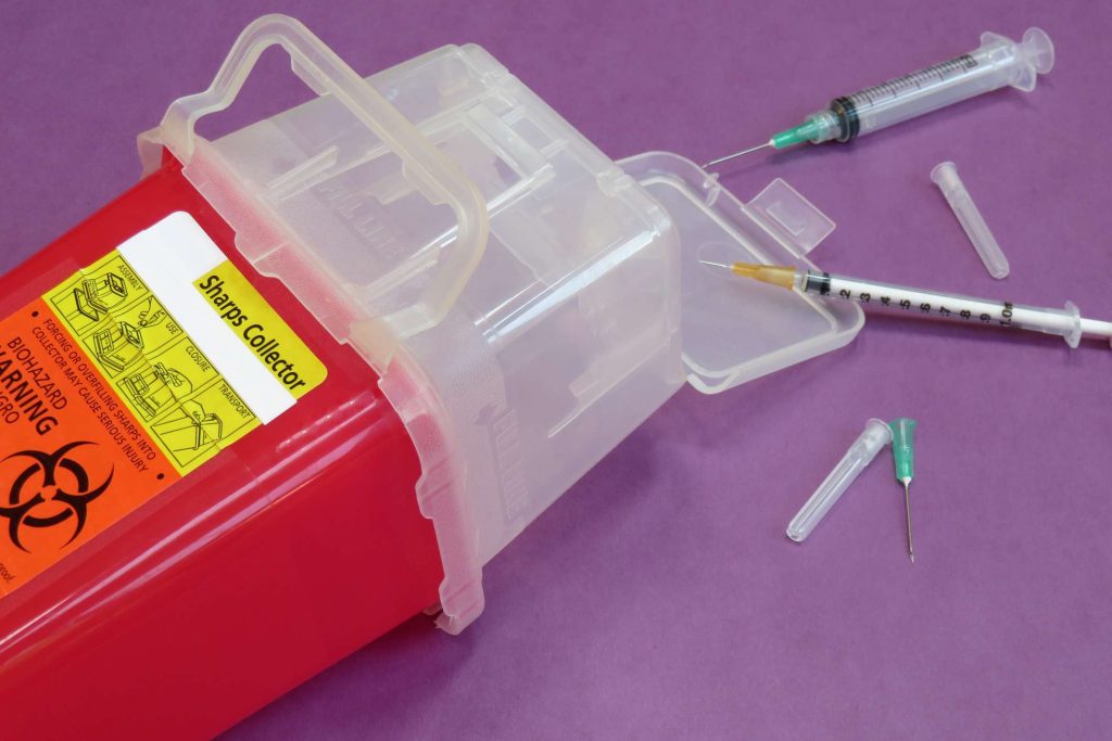 Used Needles spilt outside disposal bucket