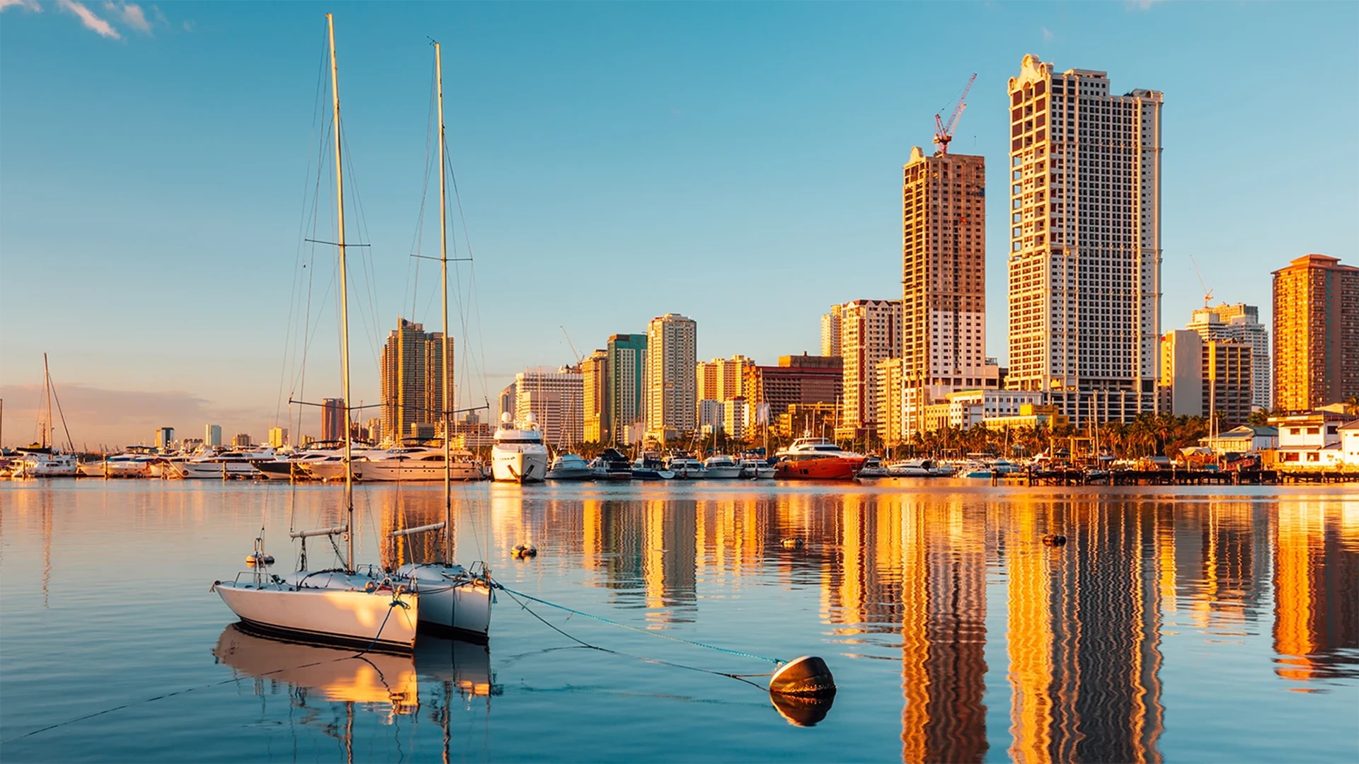 picture of a harbor at sunset with boats and city skyline in background