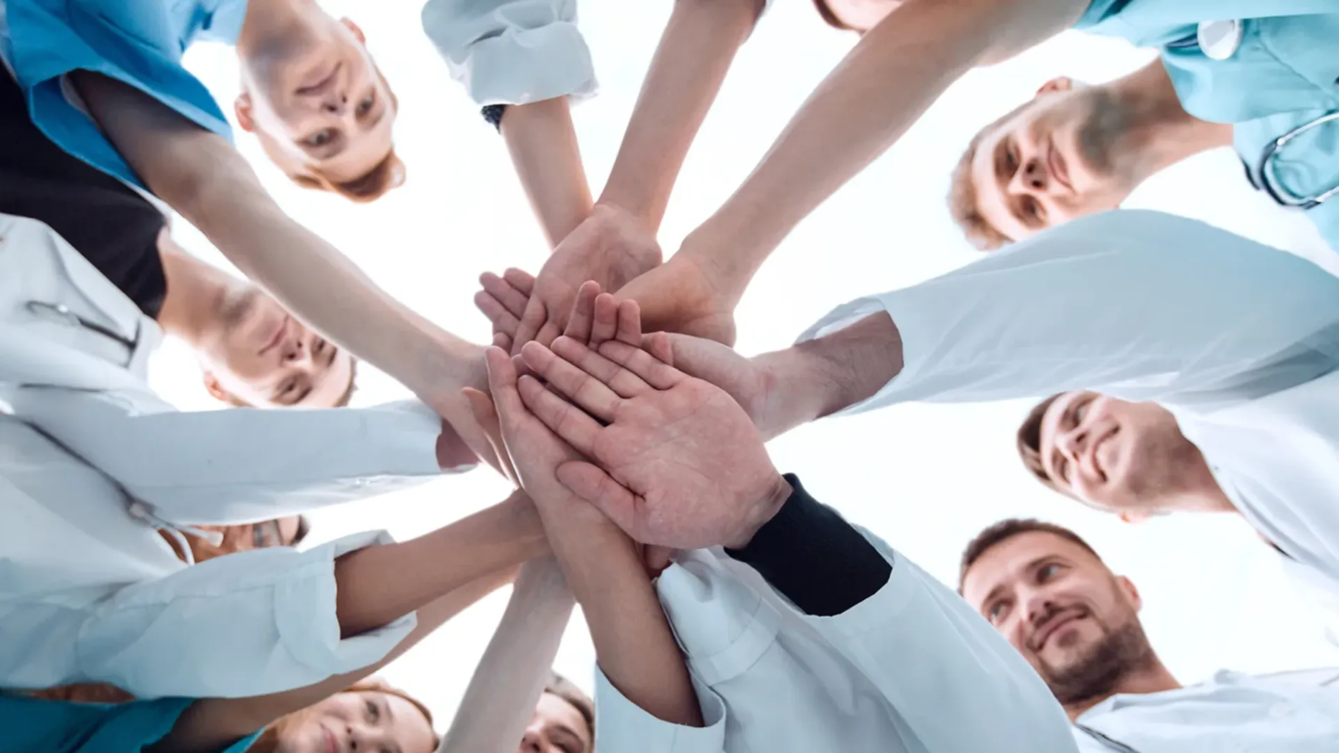 Undershot of medical team with hands together like a team huddle